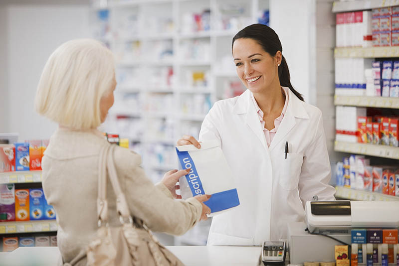 Pharmacist handing customer prescription in drug store