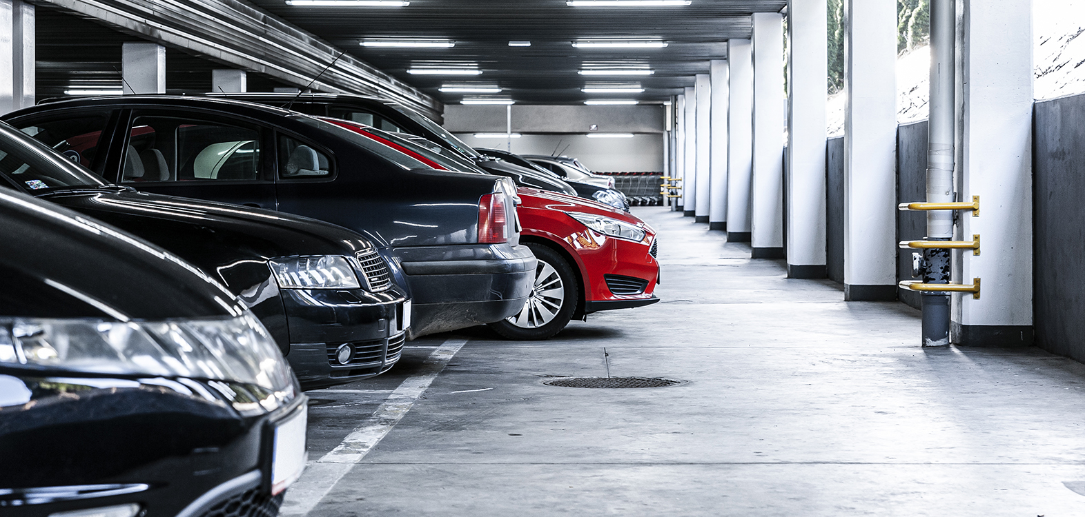 Red car paked in underground garage with lots of vehicles
